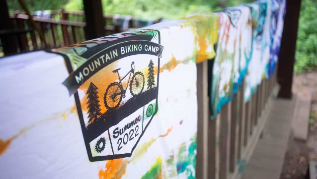 Tie dye t - shirts hanging on a railing.